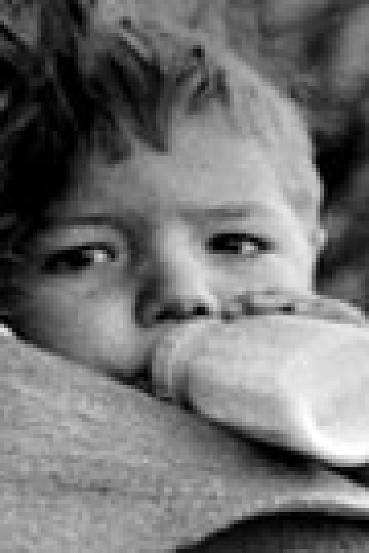 Ein Kind trinkt aus einer Flasche, gehalten von einer Person.