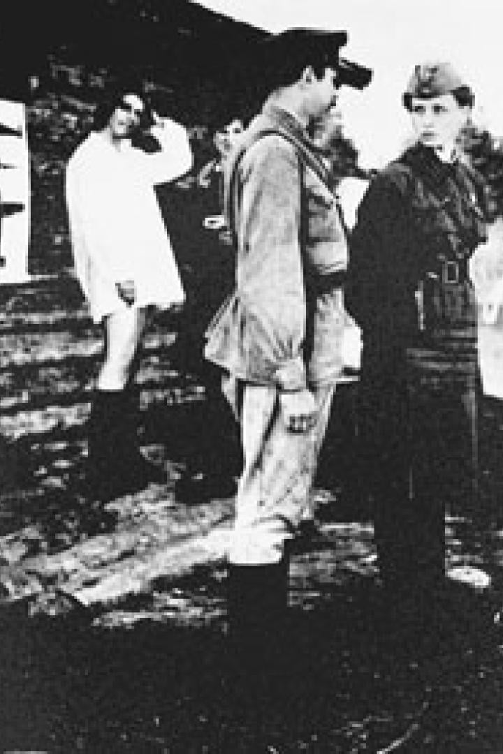 Eine Gruppe von Soldaten und Zivilisten steht im Freien, einige mit Gewehren.