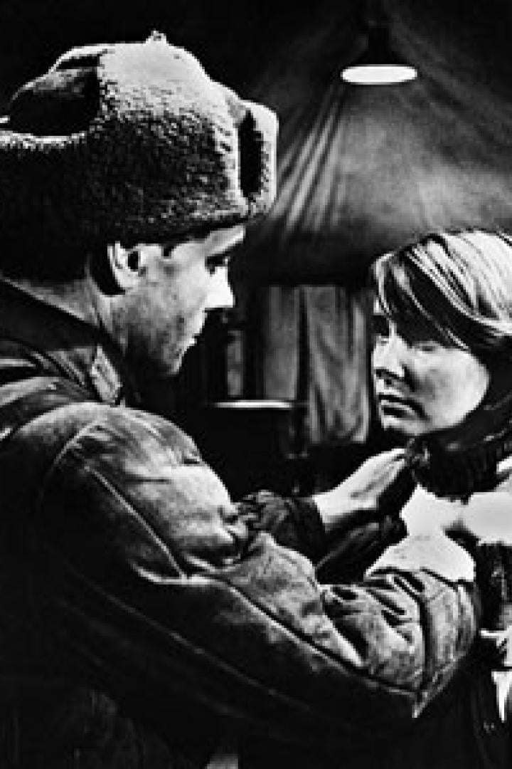 Ein Mann in Uniform und Mütze richtet den Kragen einer jungen Frau.