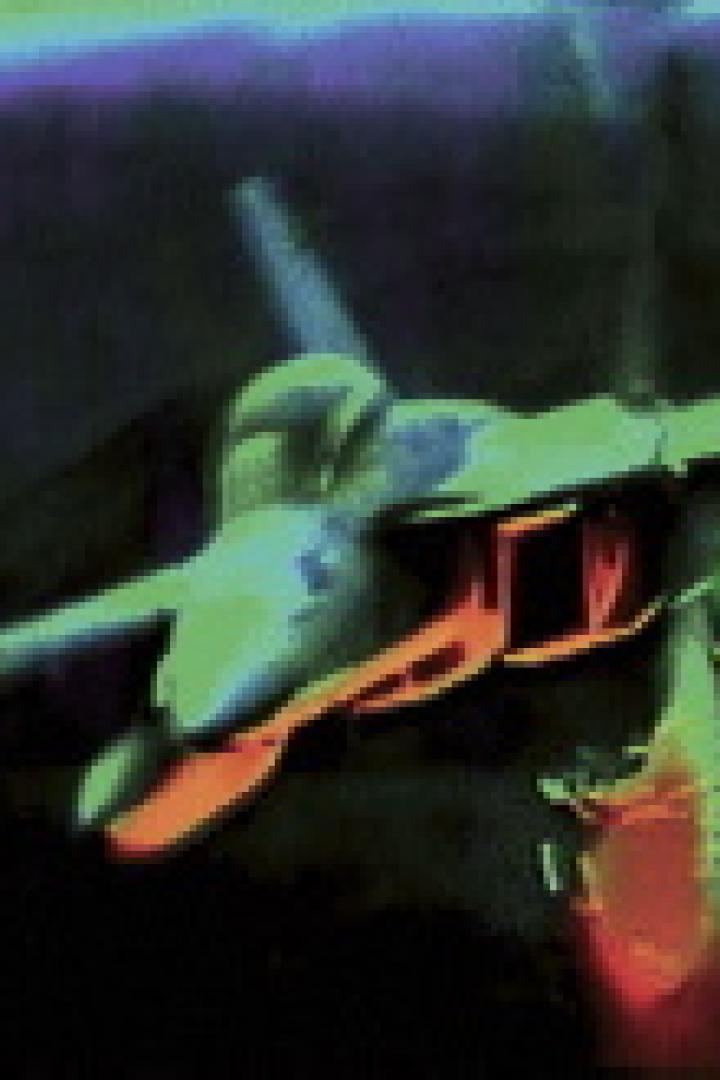 Ein Kampfjet fliegt in der Dunkelheit und schießt Leuchtspurmunition ab.