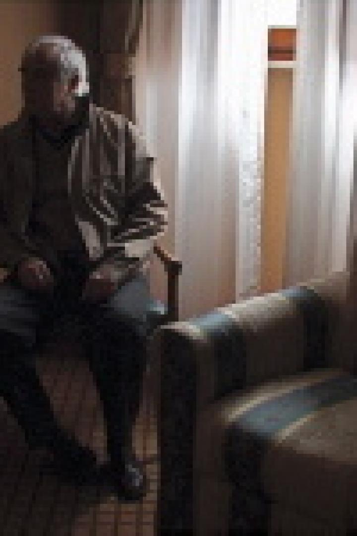 Ein älterer Mann sitzt in einem Zimmer auf einem Stuhl.