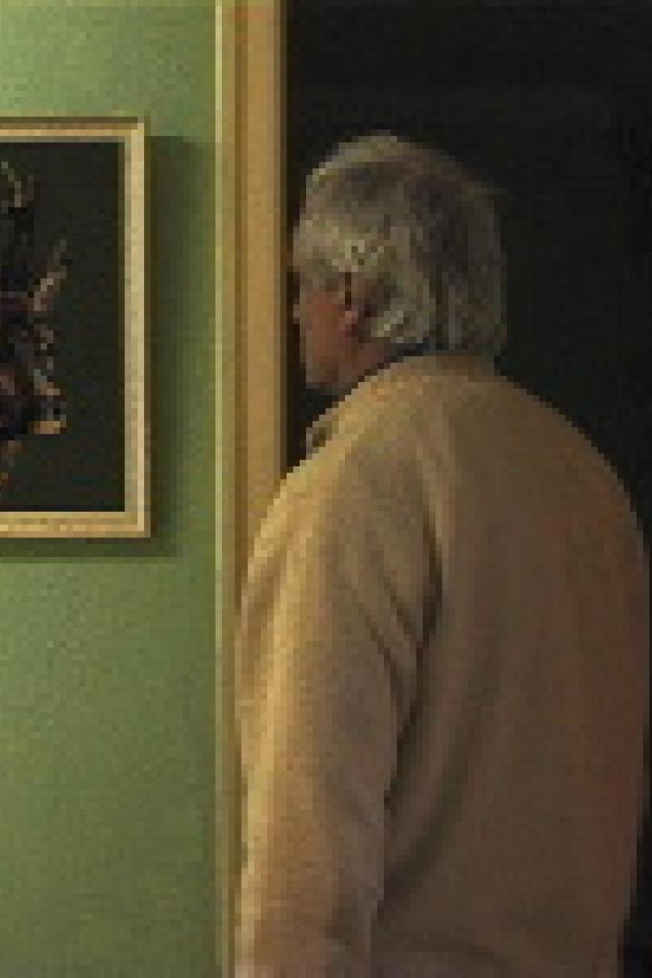 Ein Mann betrachtet ein Gemälde von einem Reh an einer grünen Wand.