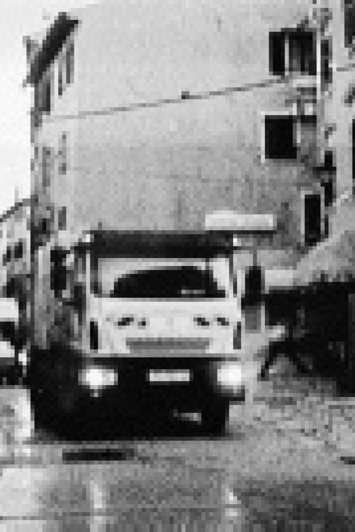 Ein Müllwagen fährt durch eine enge Gasse in einer Stadt.