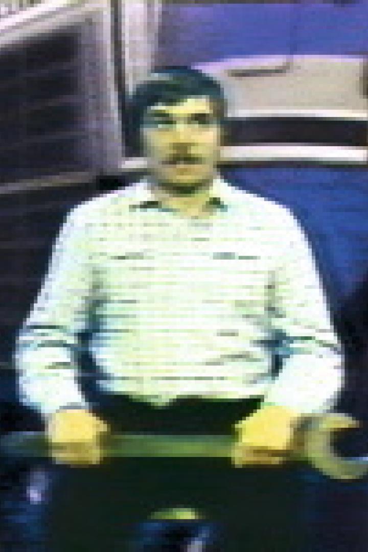 Ein Mann mit Schnurrbart hält einen großen Schraubenschlüssel vor einem Bus.