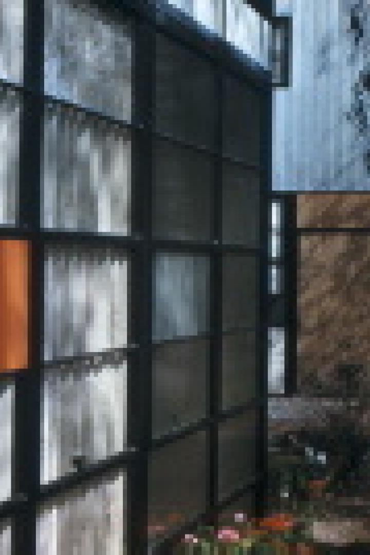 Außenansicht eines modernen Hauses mit großen Fensterflächen und farbigen Paneelen.