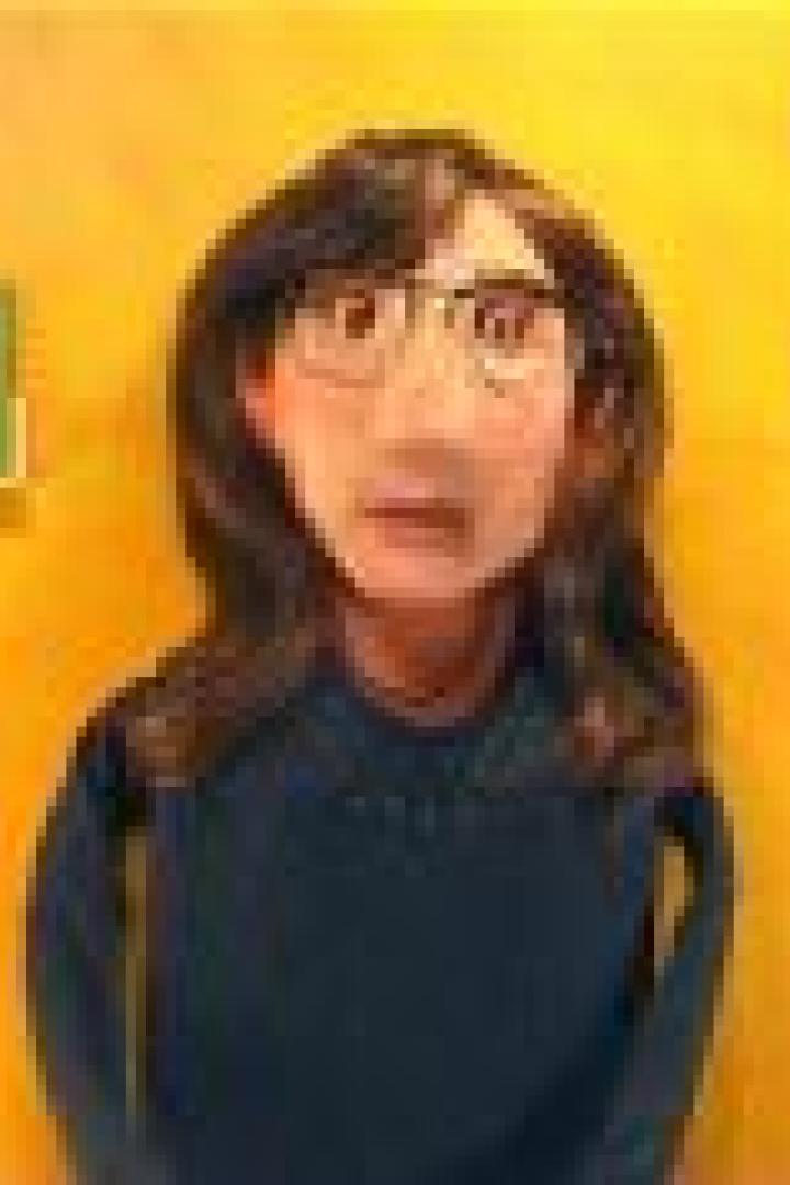 Eine Tonfigur einer Frau mit Brille vor einer gelben Wand.