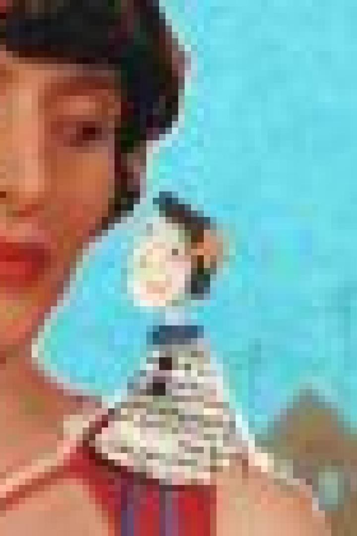 Eine Frau mit rotem Stirnband lächelt eine kleine Puppe auf ihrer Schulter an.