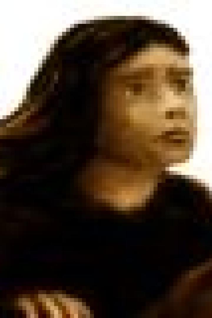 Ein junges Mädchen mit dunklen Haaren reitet auf einem Pferd.