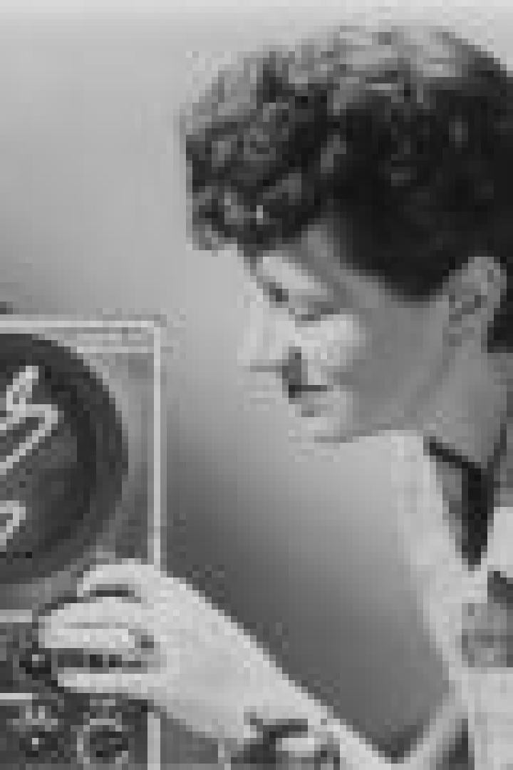 Eine Frau bedient ein Oszilloskop mit einer wellenförmigen Darstellung auf dem Bildschirm.