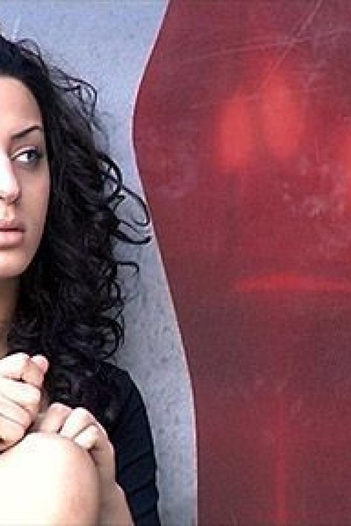 Eine junge Frau mit lockigem Haar sitzt neben einem roten High-Heel-Schuh-Graffiti.