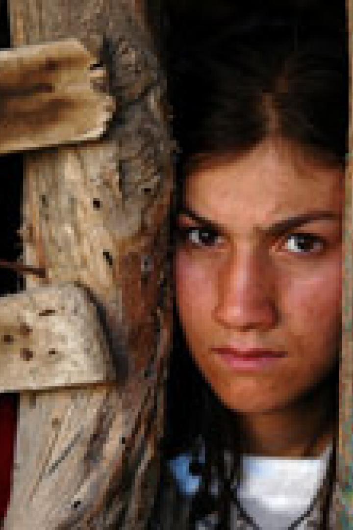 Ein junges Mädchen steht in einer Türöffnung und blickt ernst in die Kamera.