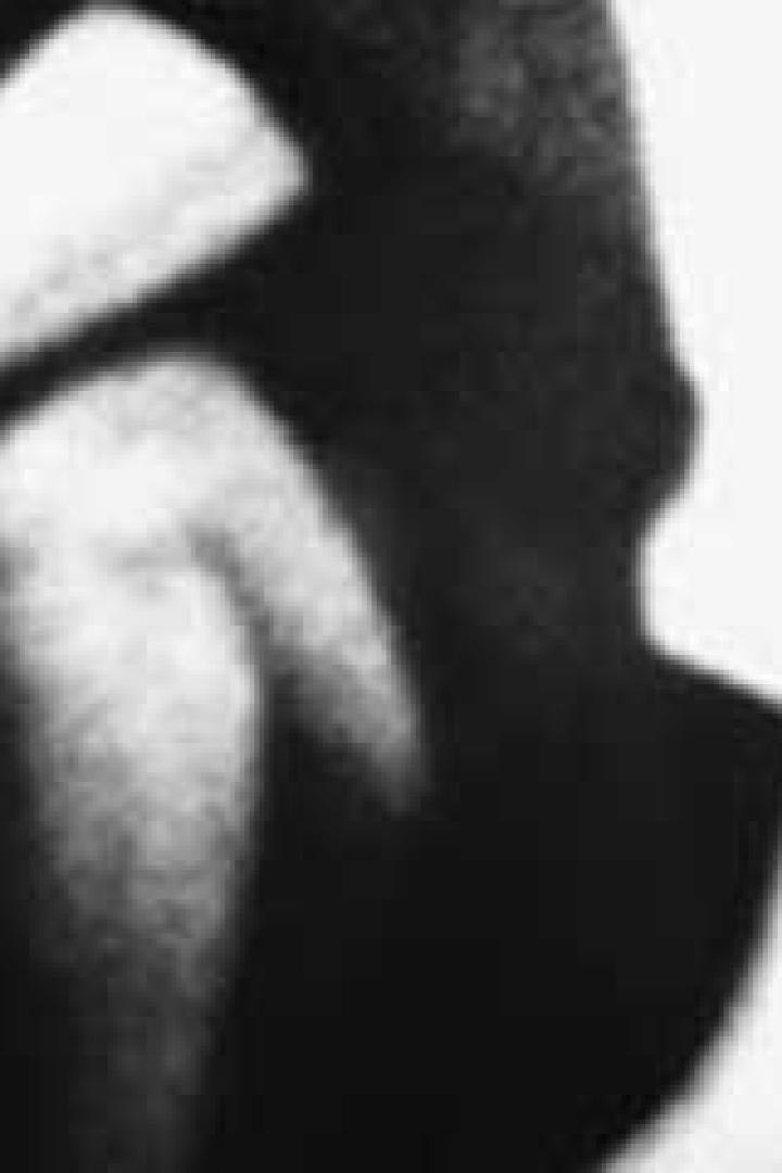 Nahaufnahme einer Person, die im Dunkeln sitzt.