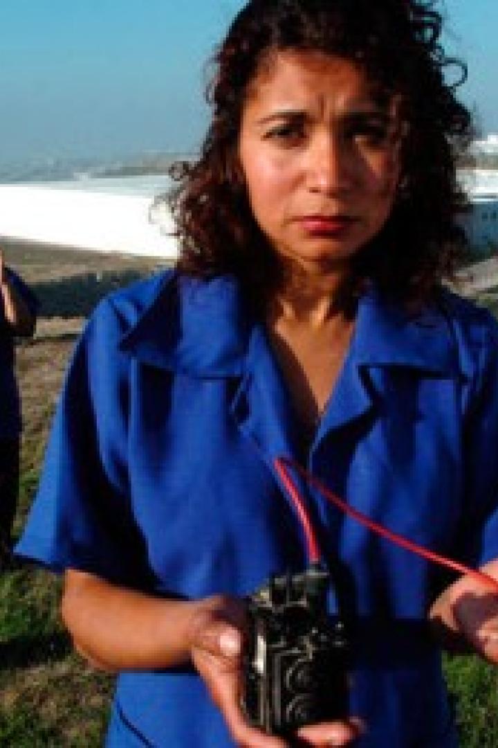 Eine Frau hält ein elektronisches Gerät in den Händen, während andere Frauen im Hintergrund stehen.