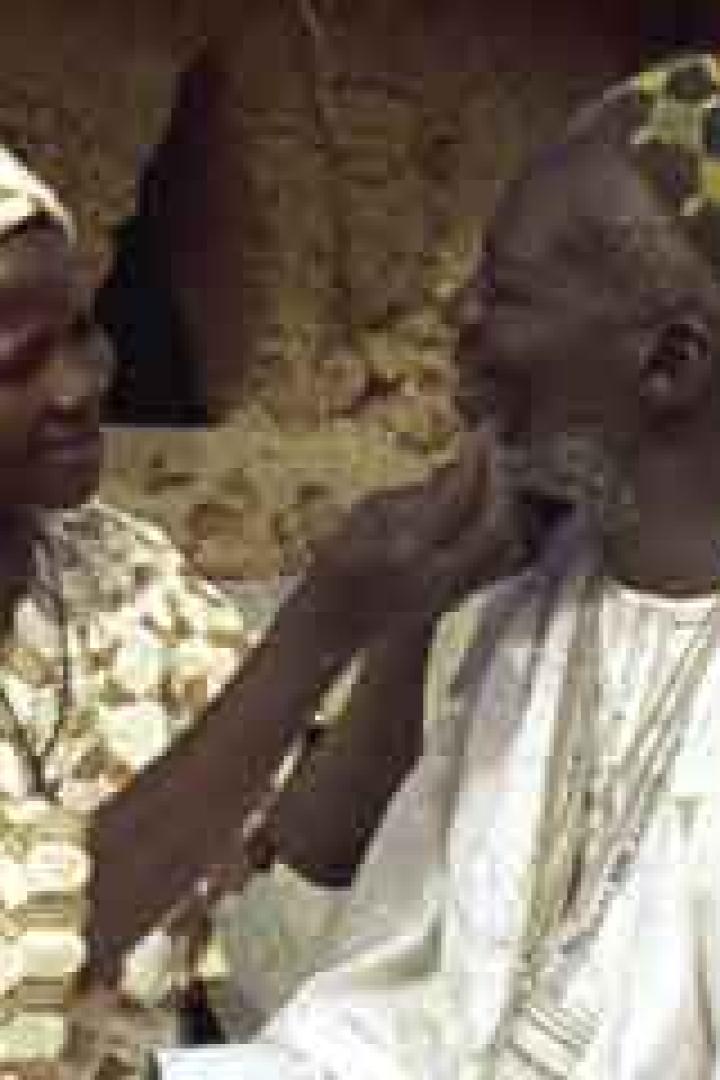 Eine Frau berührt den Bart eines älteren Mannes im Freien.