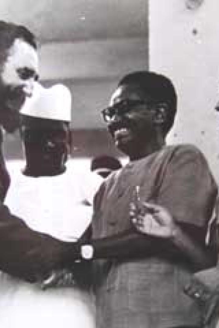 Fidel Castro schüttelt die Hand eines Mannes, umgeben von weiteren Personen.