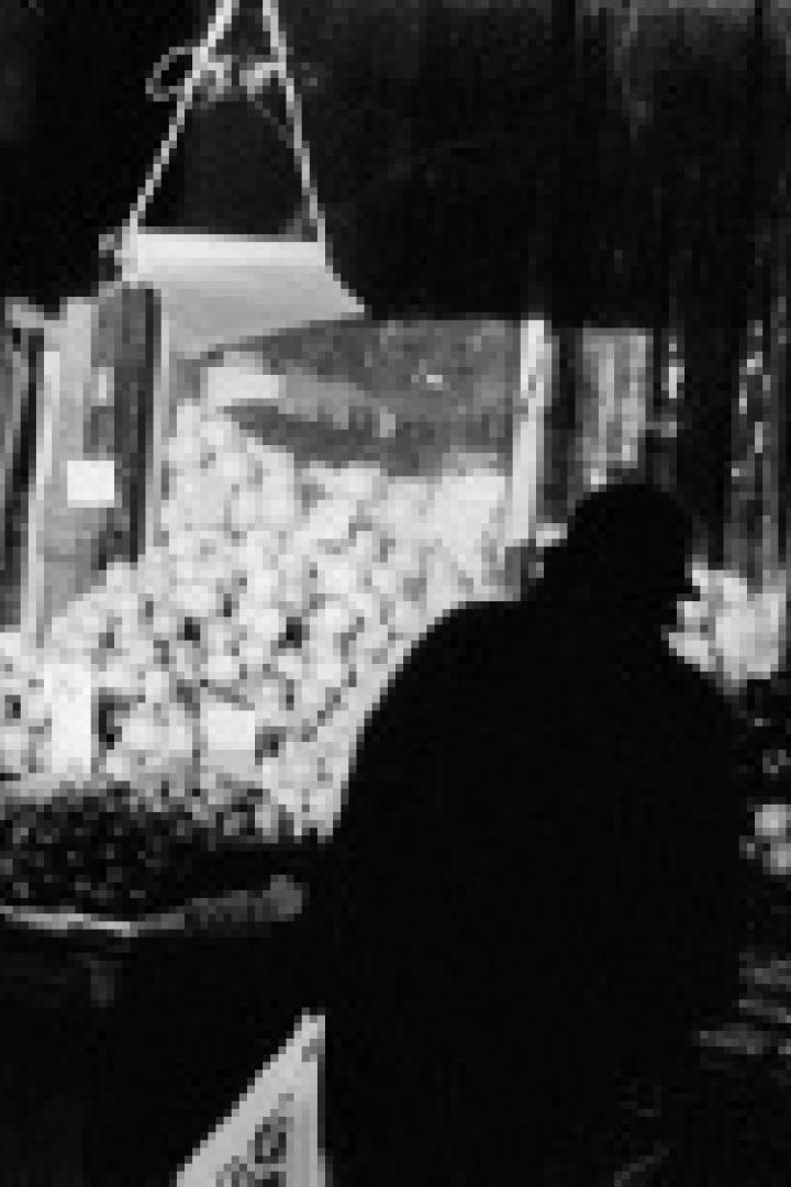 Ein Mann steht vor einem Marktstand mit Obst und Gemüse.