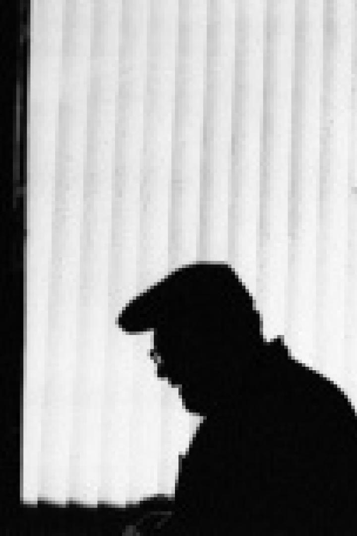 Die Silhouette eines Mannes mit Hut vor einem Fenster.