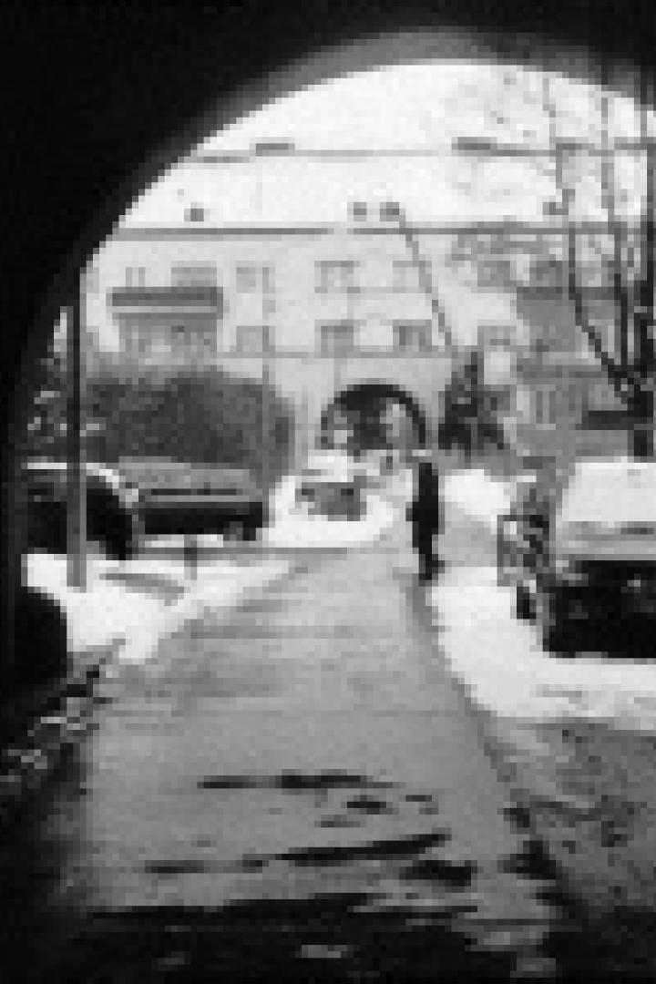 Ein verschneiter Durchgang mit Blick auf eine Straße und ein Gebäude im Hintergrund.