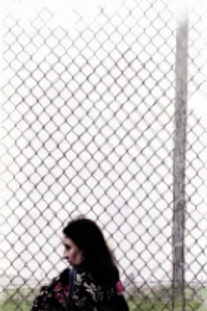 Eine Frau geht an einem Maschendrahtzaun entlang.