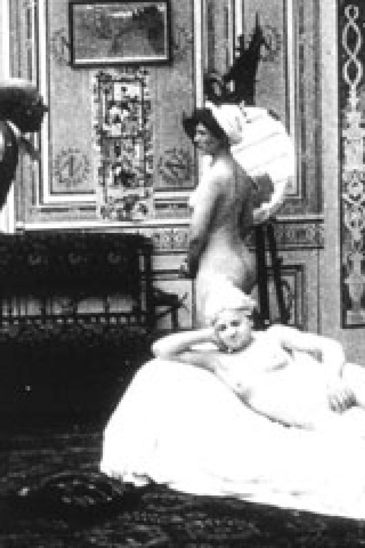 Eine Aktstudie mit zwei Frauen in einem Atelier, eine liegend, die andere stehend vor einer Staffelei.