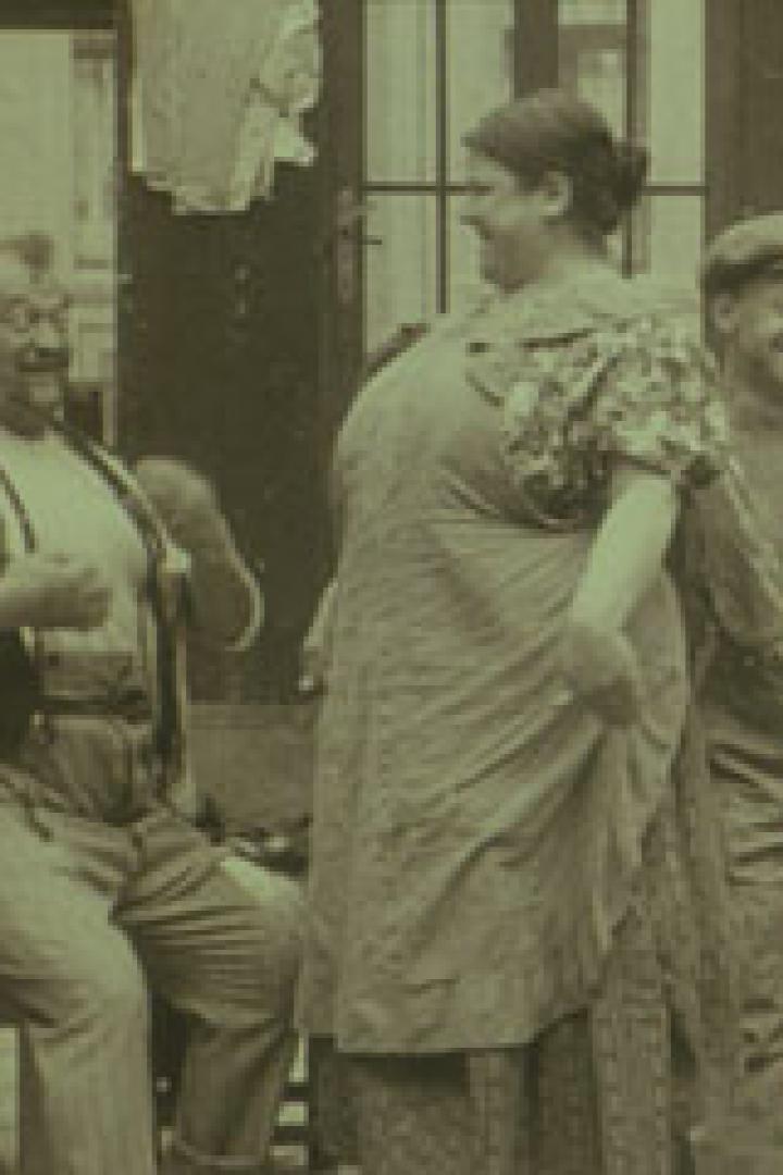 Eine beleibte Frau steht zwischen zwei Männern in einer Werkstatt.