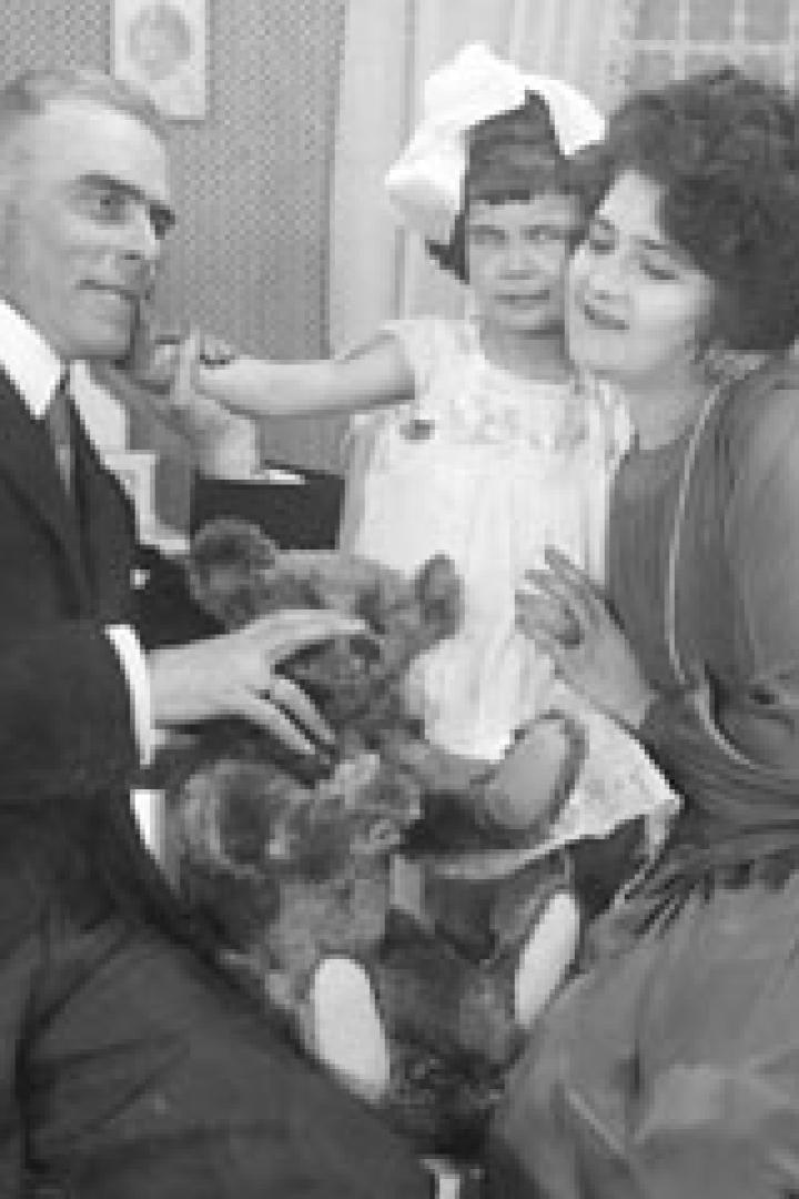 Eine Familie sitzt zusammen und spielt mit einem Teddybären.