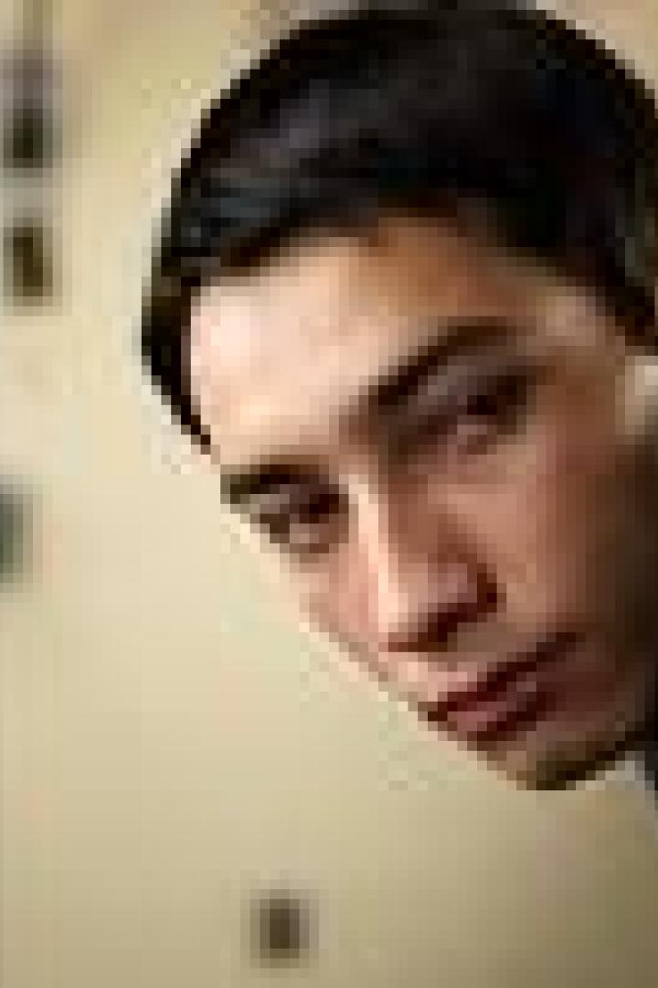 Ein junger Mann schaut aufmerksam aus dem Hintergrund.