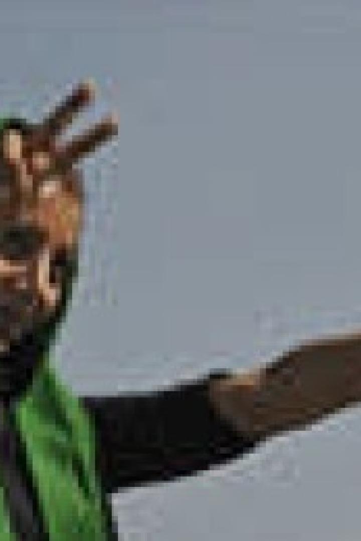 Eine Frau mit grünem Kopftuch zeigt das Victory-Zeichen.