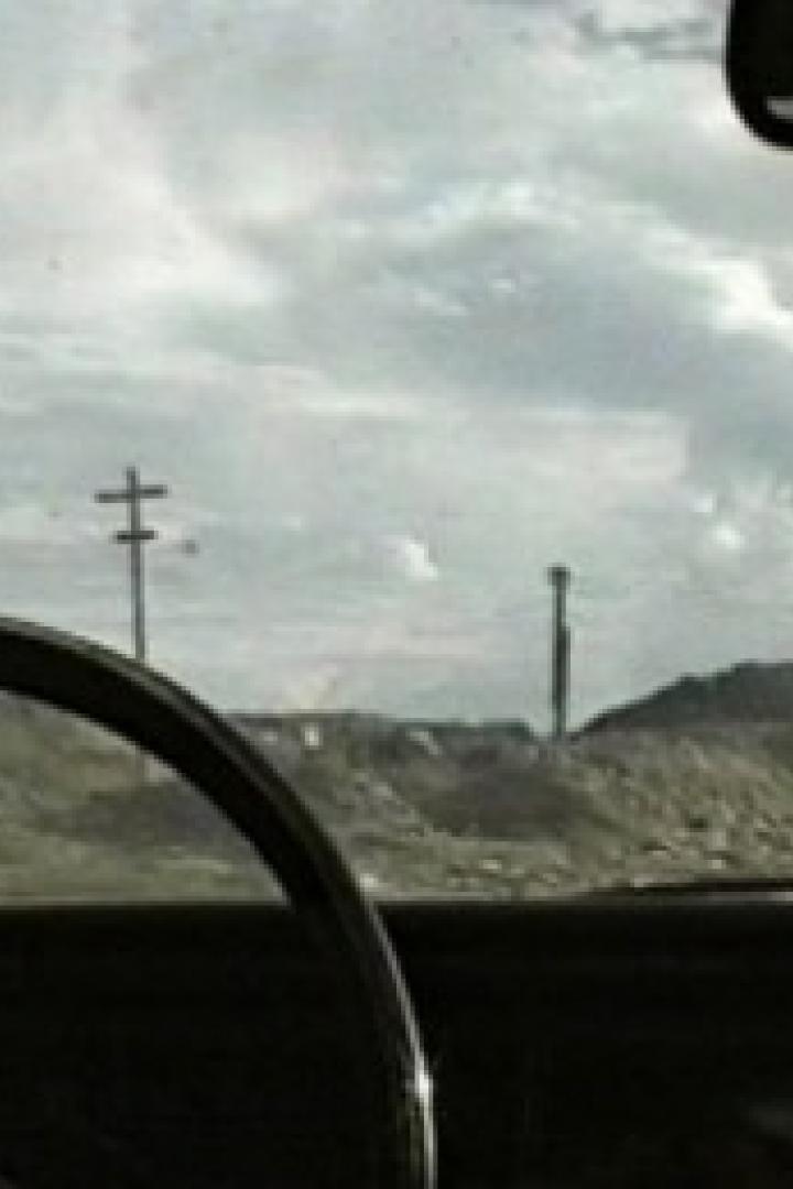 Eine Person fährt durch eine trockene Landschaft mit bewölktem Himmel.