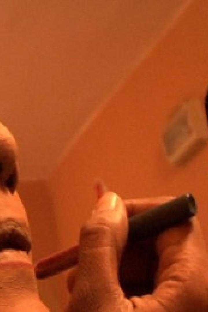 Eine Person schminkt sich mit einem Lippenstift vor einem Spiegel.