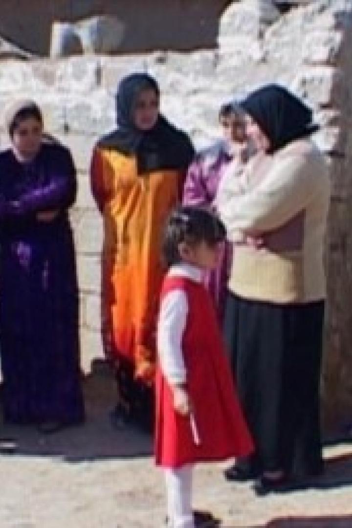 Eine Gruppe von Frauen und Kindern steht im Freien vor einem Gebäude.