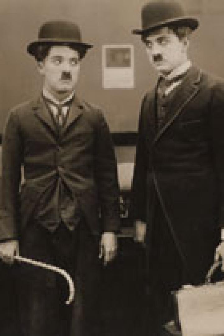 Charlie Chaplin und ein weiterer Mann, beide mit Melone und Schnurrbart, stehen nebeneinander.