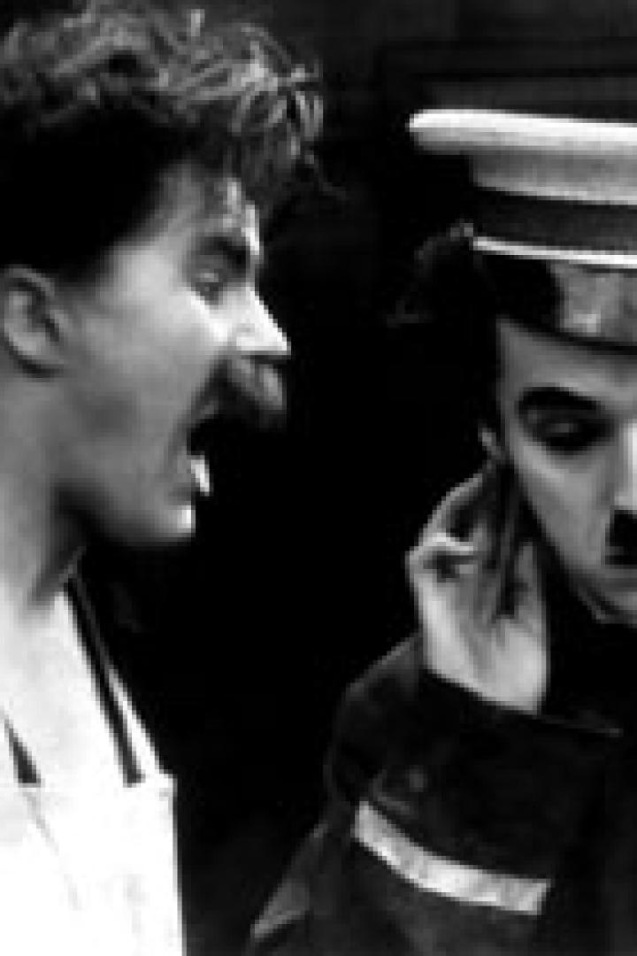 Charlie Chaplin als Soldat mit einem schreienden Mann im Hintergrund.
