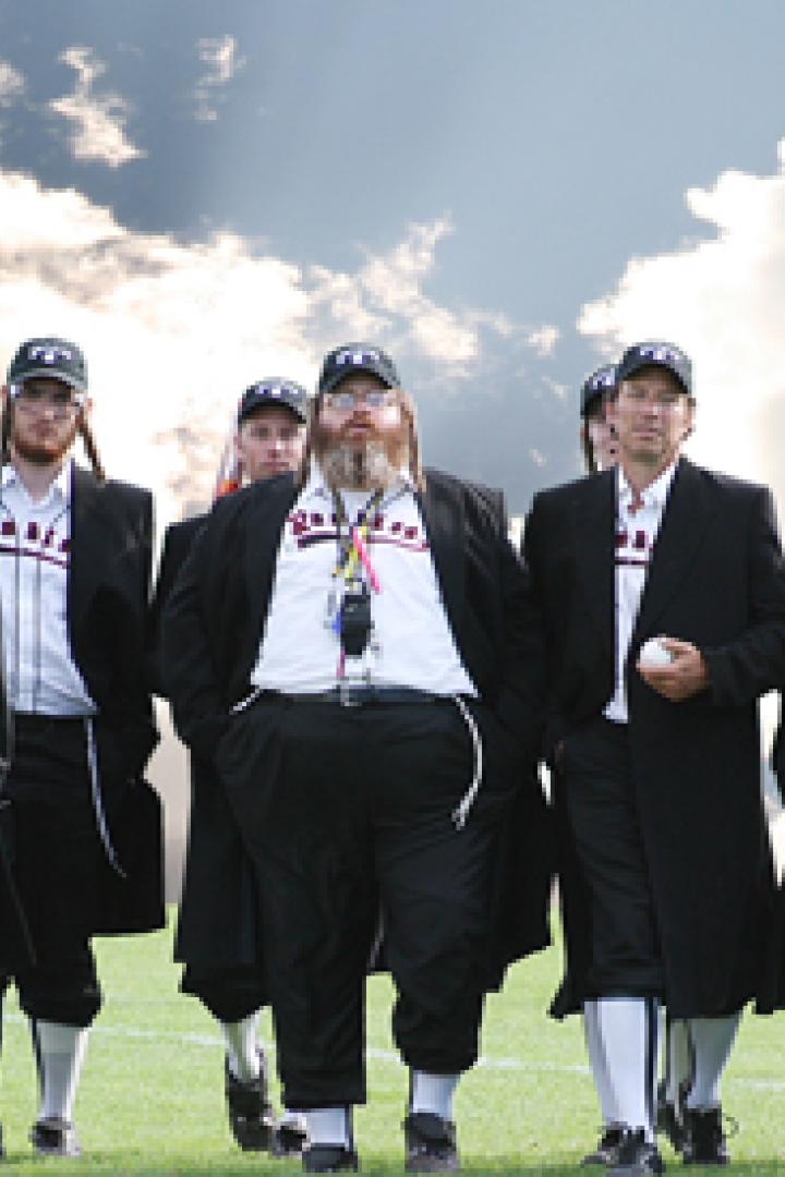 Eine Gruppe von Männern in Baseballuniformen und schwarzen Mänteln steht auf einem Feld.