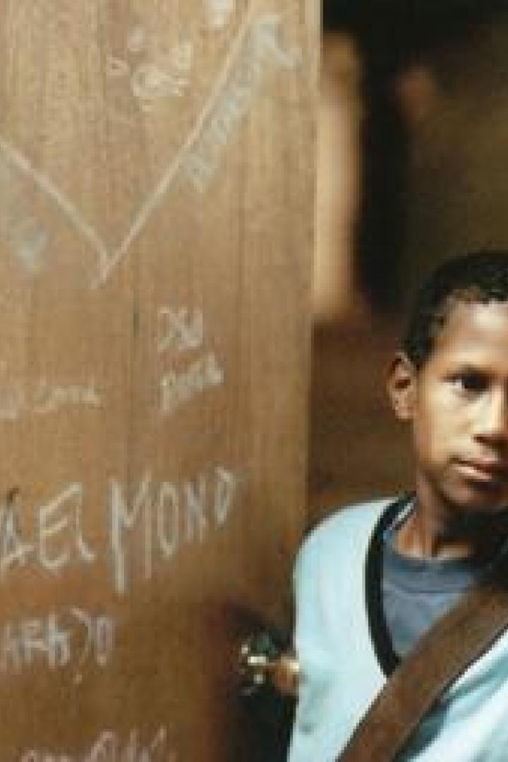 Ein junger, dunkelhäutiger Junge steht in einer Türöffnung.