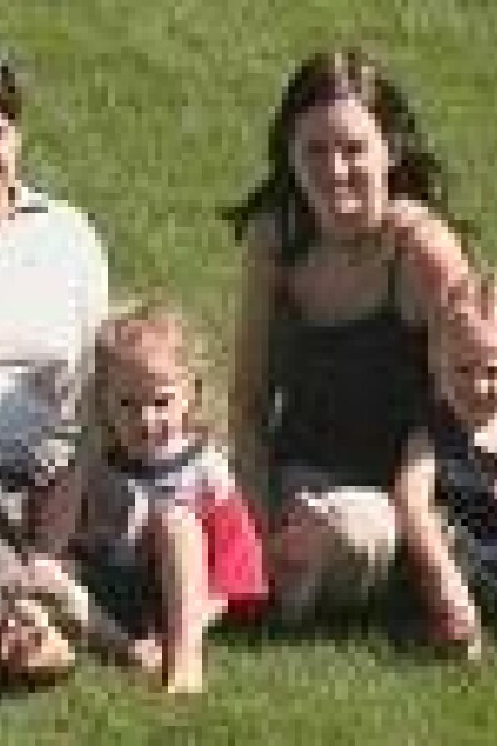 Zwei Frauen sitzen mit zwei kleinen Kindern auf einer Wiese.