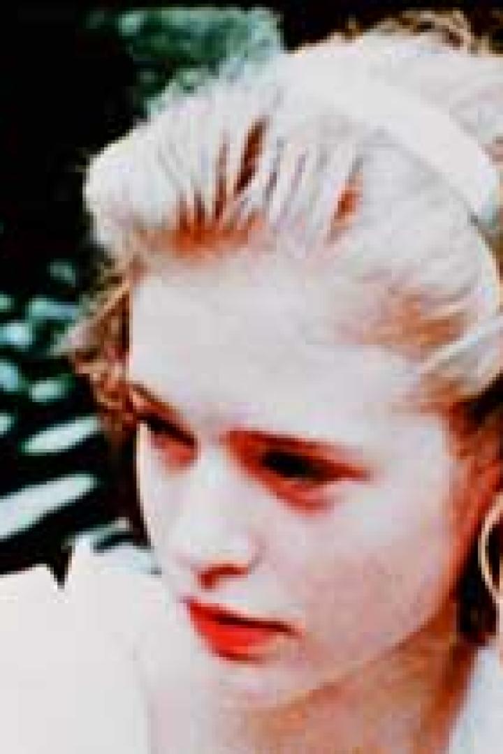 Eine junge Frau mit blonden Haaren und einem Haarband blickt nach links.