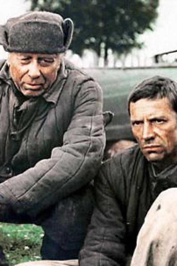 Zwei Männer in Arbeitskleidung sitzen im Freien.