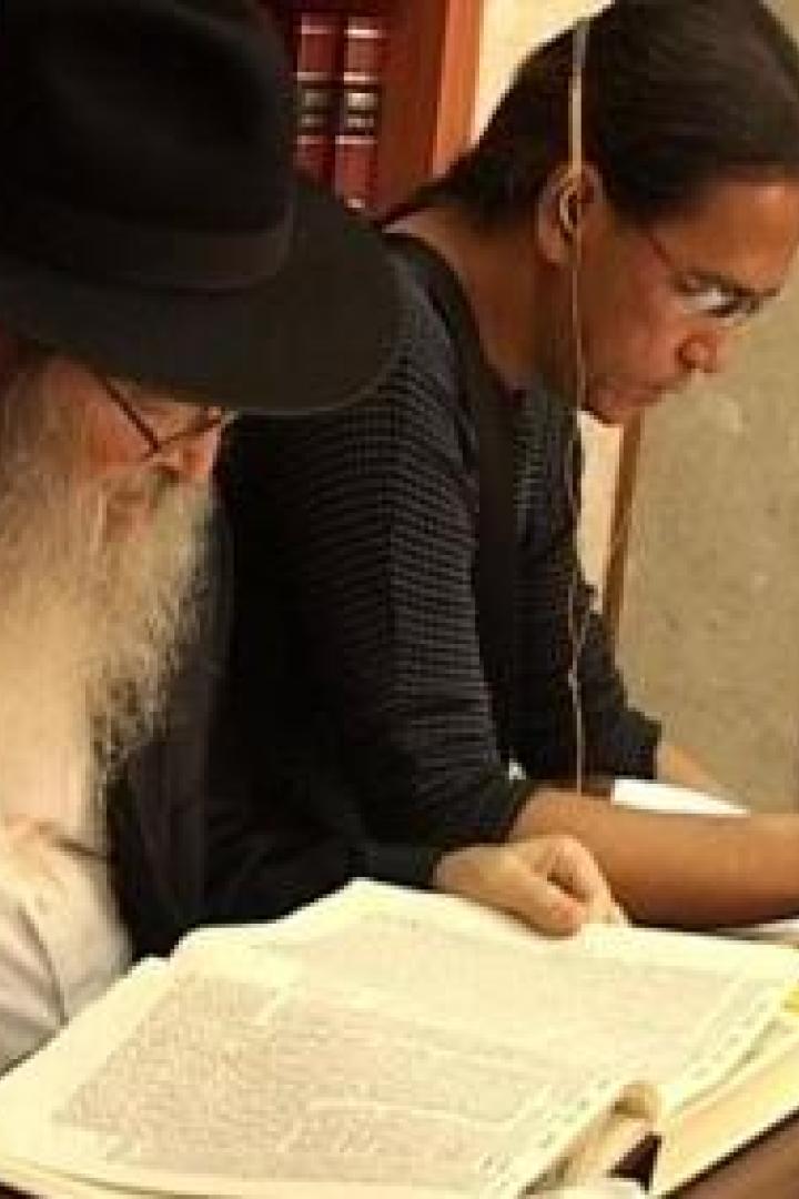 Zwei Männer sitzen an einem Tisch und studieren ein Buch.