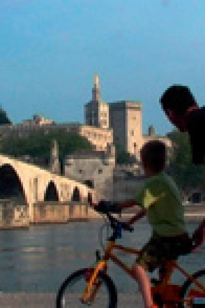 Ein Vater lehrt seinem Sohn das Fahrradfahren vor der Brücke von Avignon.