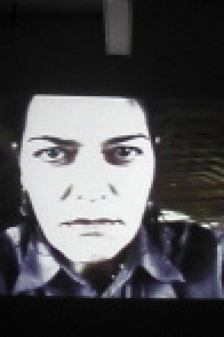 Das Gesicht einer Frau mit dunklen Haaren und ernstem Blick wird aus der Froschperspektive gezeigt.