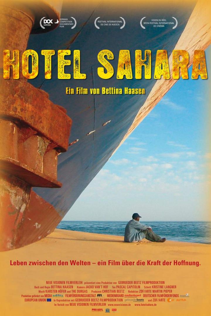 Das Filmplakat für „Hotel Sahara“ zeigt einen Mann vor einem großen Schiff.