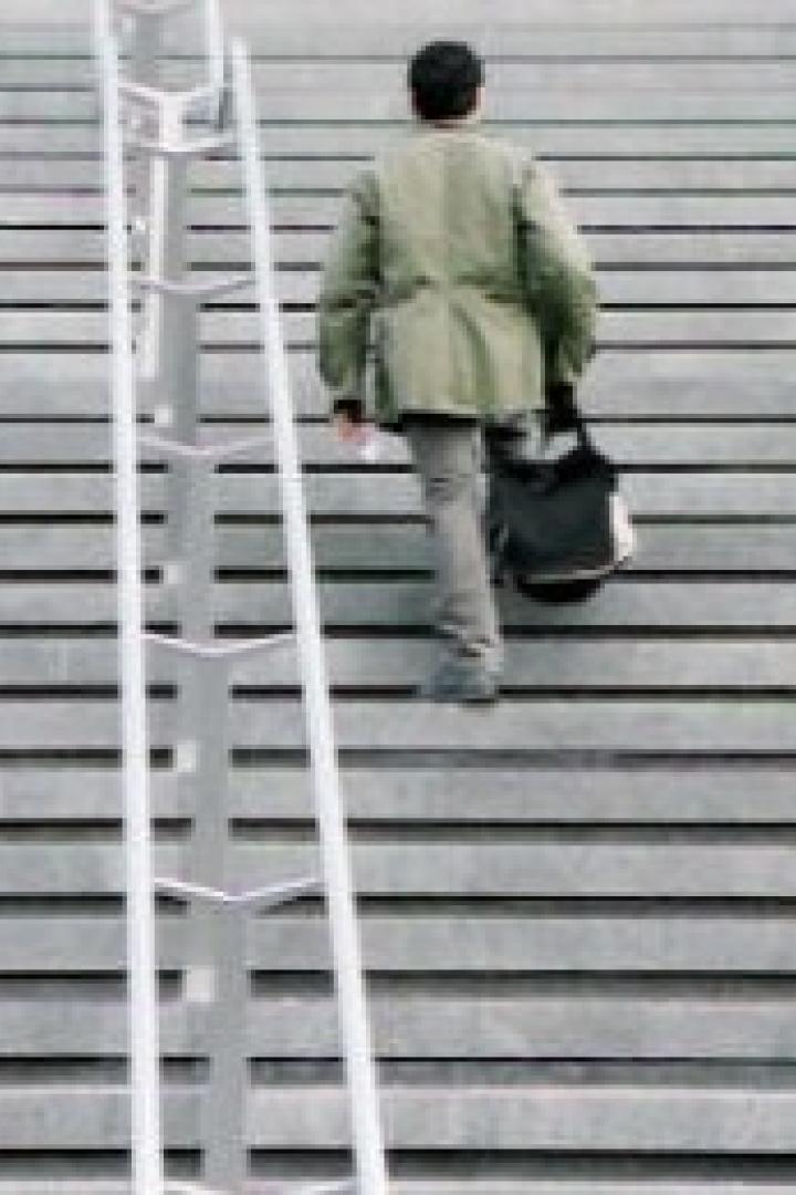 Ein Mann geht eine breite Treppe hinauf, neben ihm steht eine Leiter.