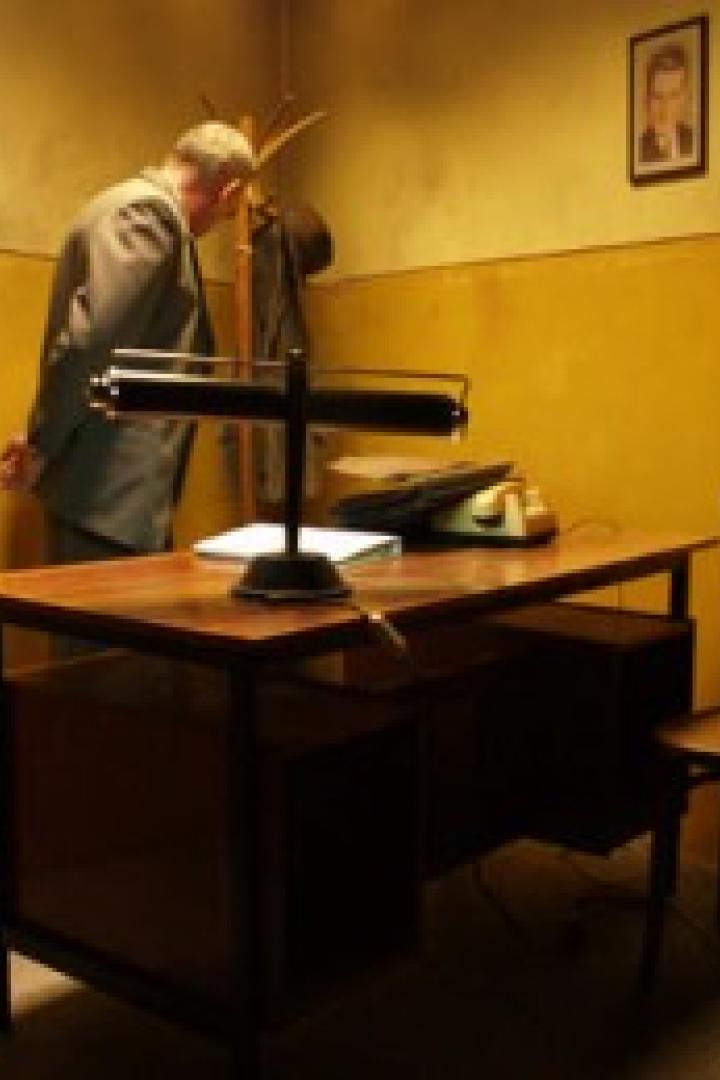 Ein Mann in einem Büro mit gelben Wänden beugt sich über einen Schreibtisch.