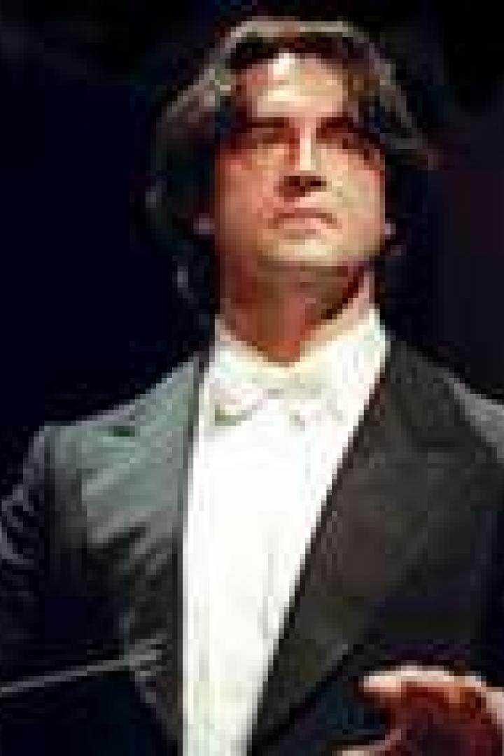 Ein Dirigent mit dunklen Haaren und einem weißen Hemd mit Fliege.