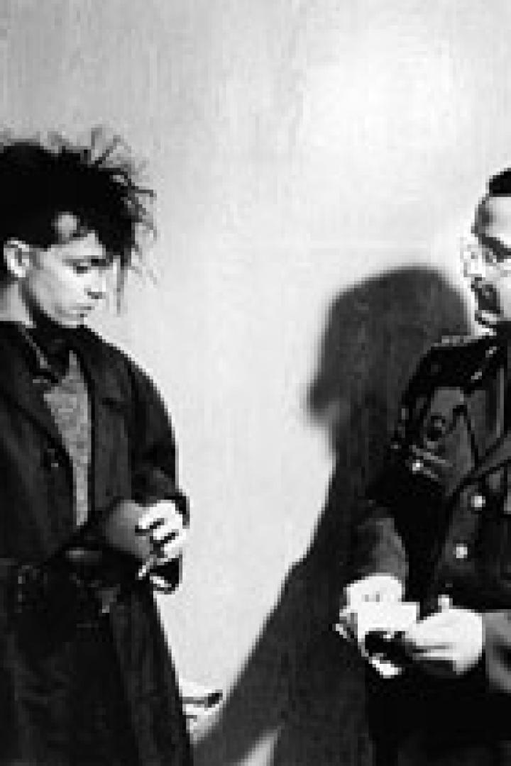 Ein junger Mann mit auffälliger Frisur wird von einem Polizisten kontrolliert.