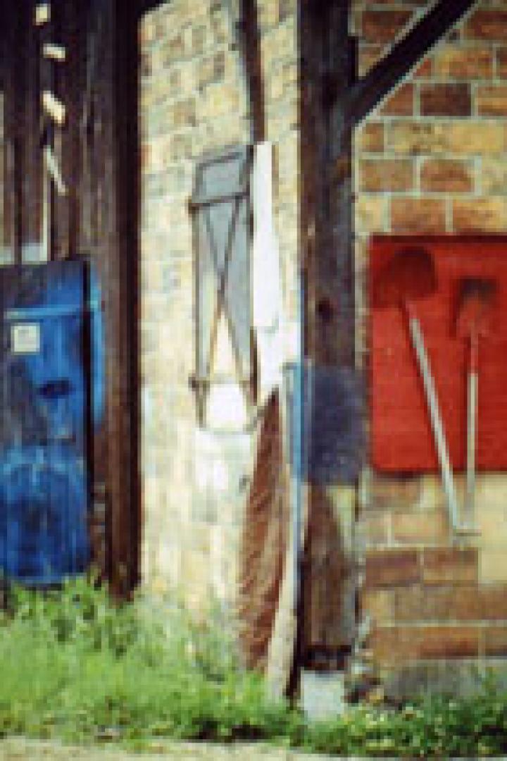 Eine rote Tafel an einer Backsteinmauer mit Schaufeln, einem Feuerlöscher und einer Spitzhacke.