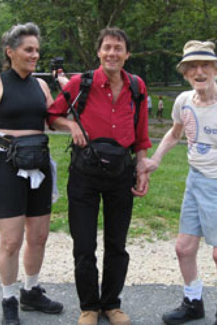 Drei Personen stehen im Freien, eine Frau, ein Mann und ein älterer Mann, alle mit Hüfttaschen.