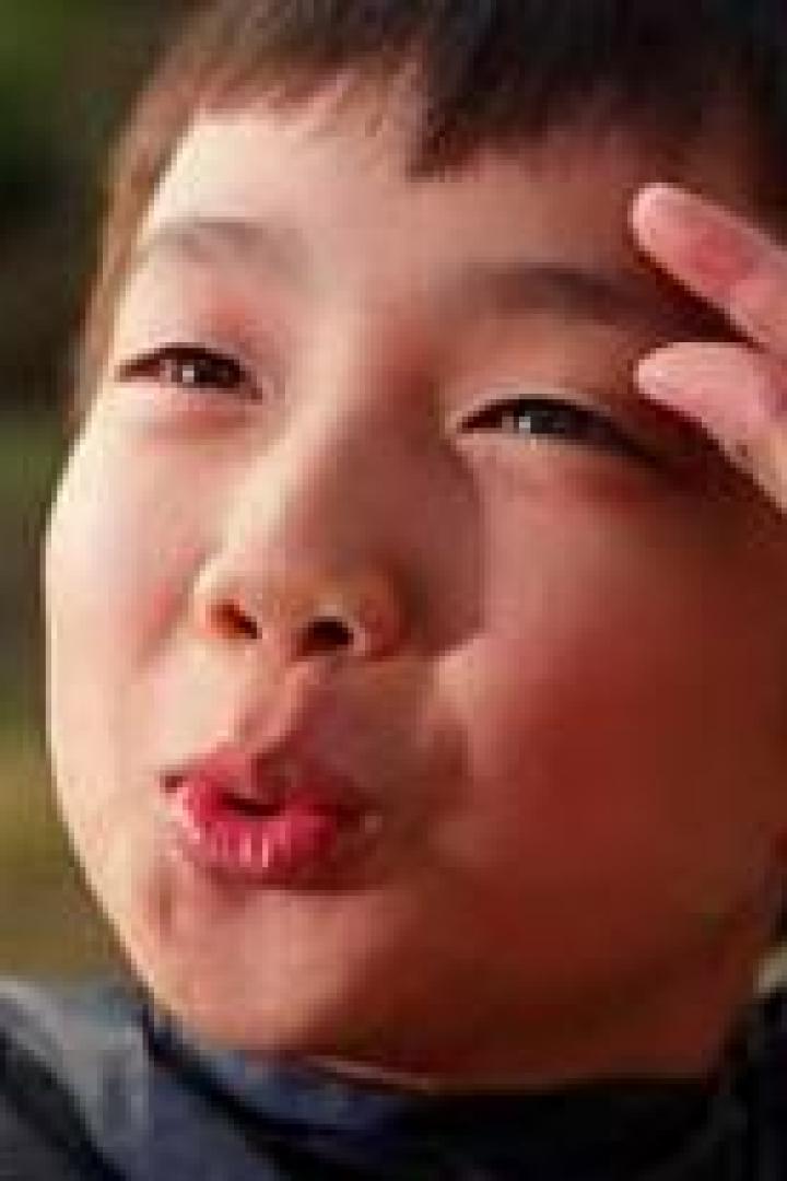 Ein Junge formt mit seinen Fingern eine kleine Geste vor seiner Stirn.