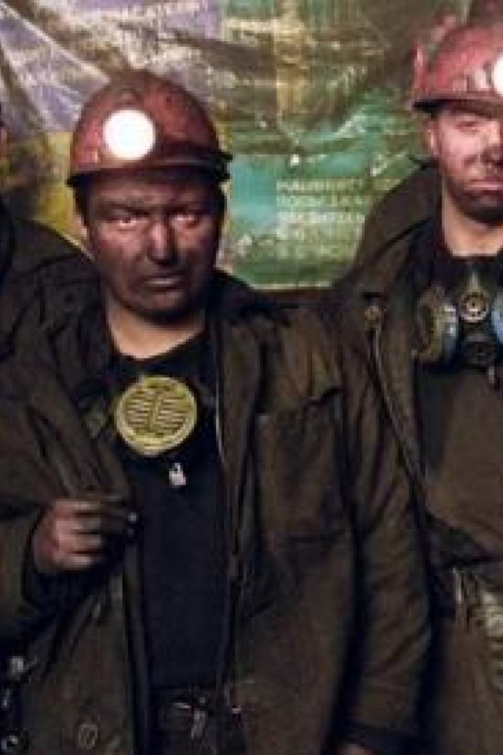 Eine Gruppe von Bergleuten mit schmutzigen Gesichtern und Helmen steht zusammen.